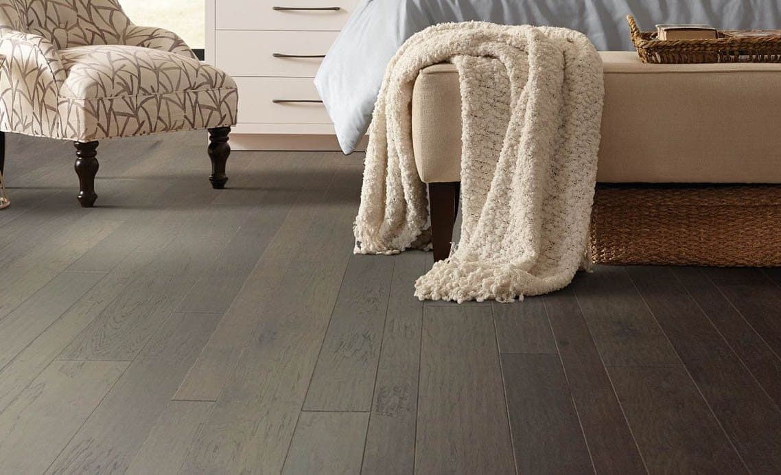 Grey rigid-core plank flooring running through a furnished bedroom