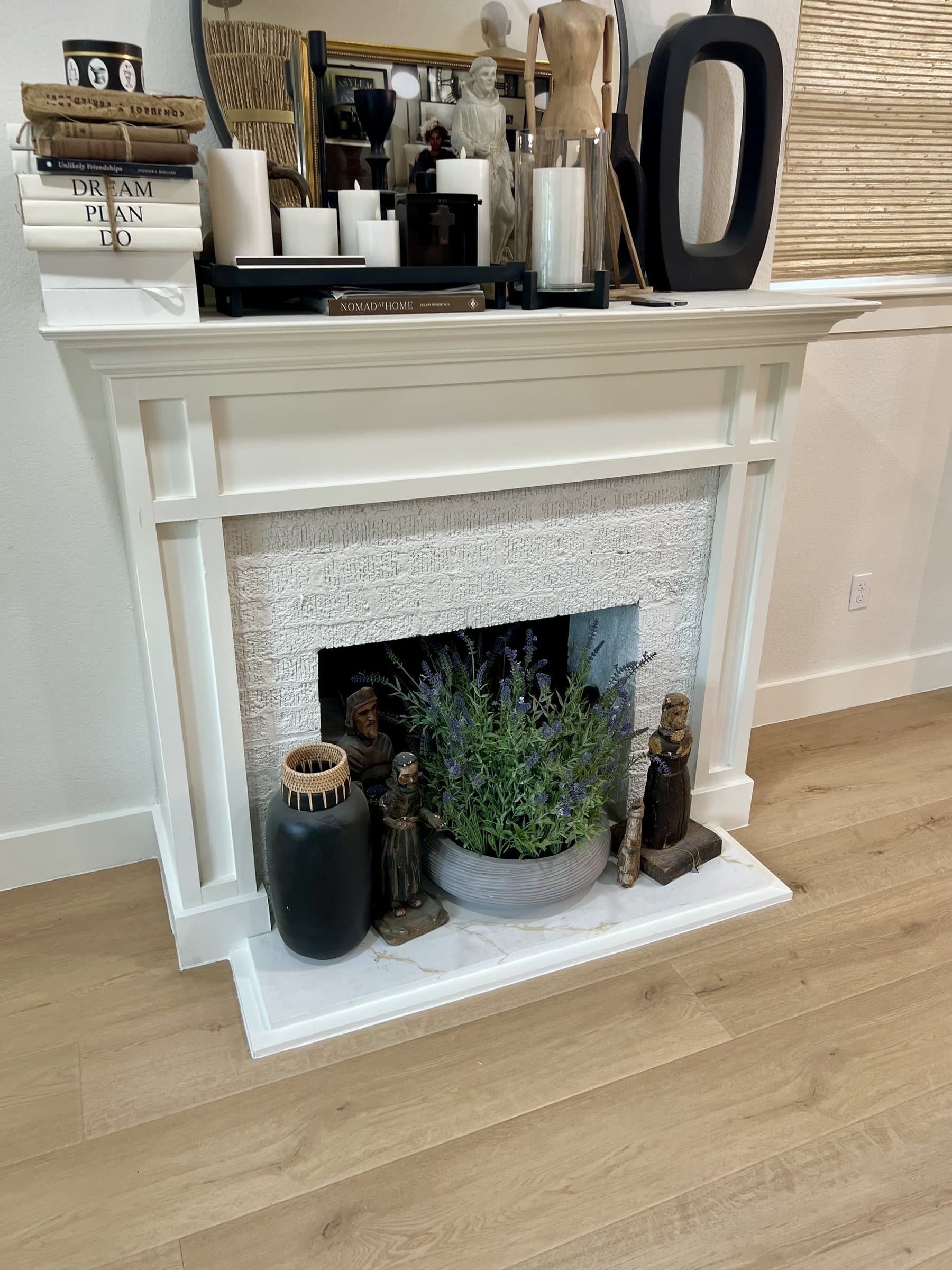 Light oak wide-plank flooring running up to a white painted fireplace surround