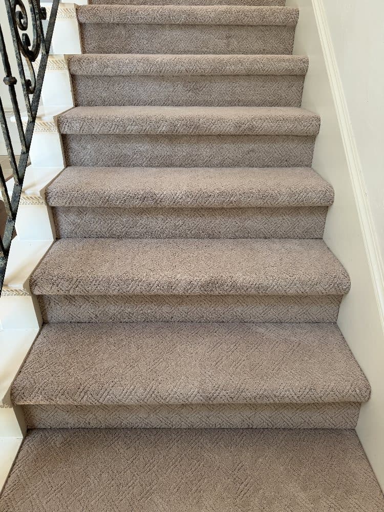Patterned neutral carpet cap-and-band installed over a run of stairs