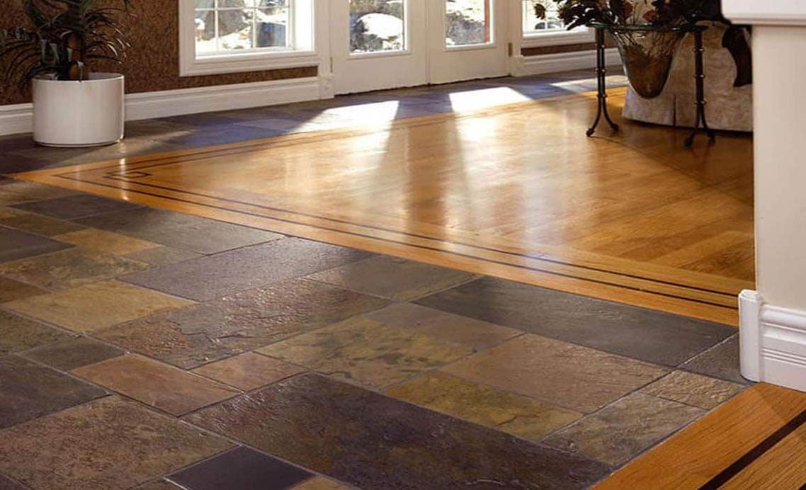 Natural stone tile meeting hardwood with a custom inlay border